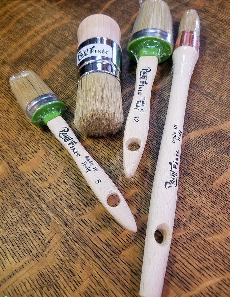 four paint pixie paint brushes laying on wood